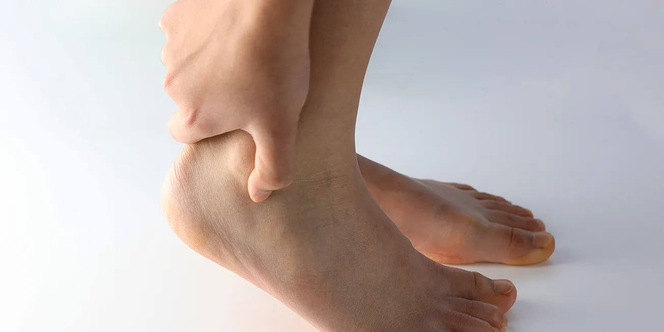 Person holder på hælen, med smerter i akillessenen.